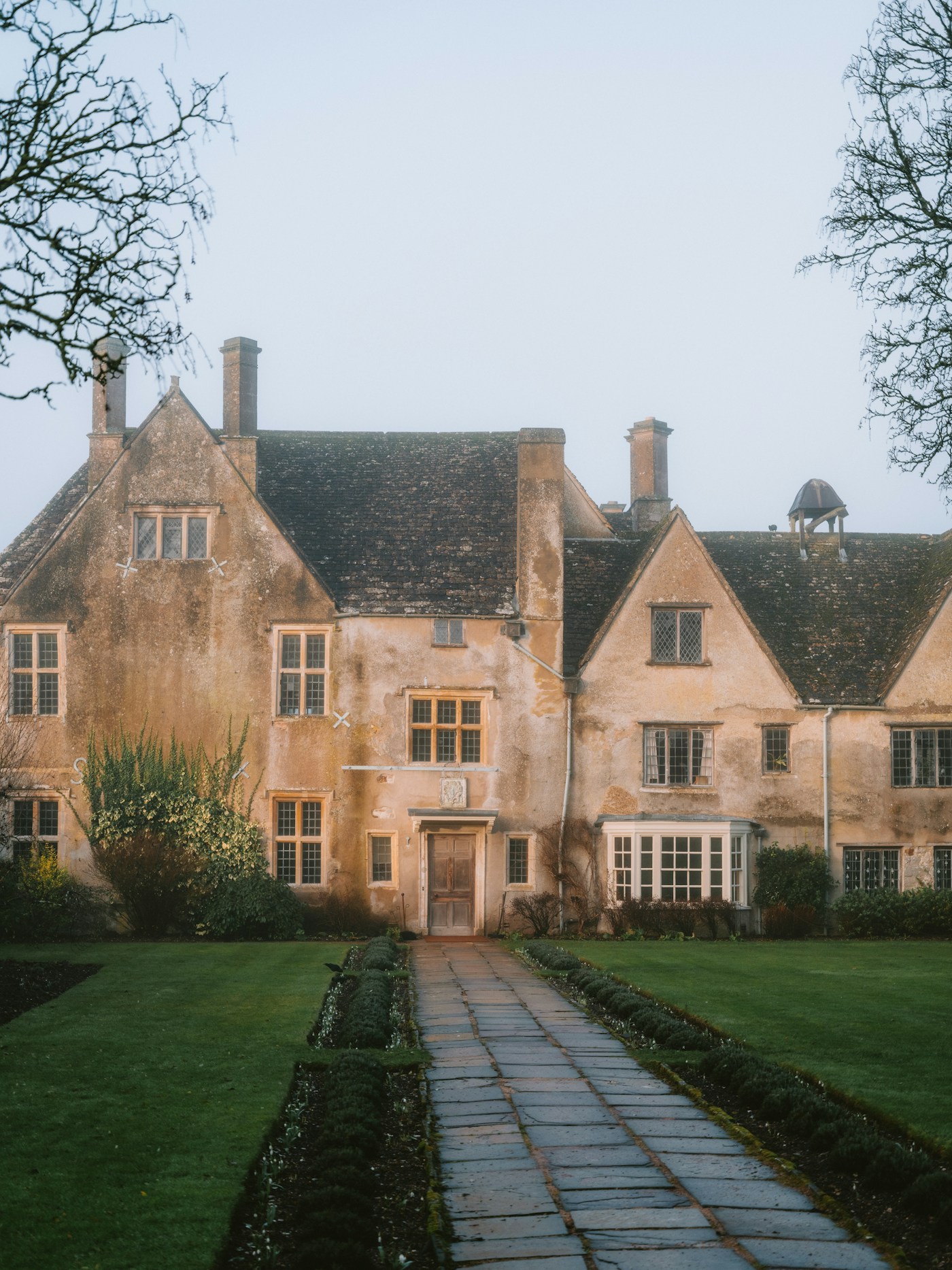 Historic stone manor house with a garden path in the English countryside.